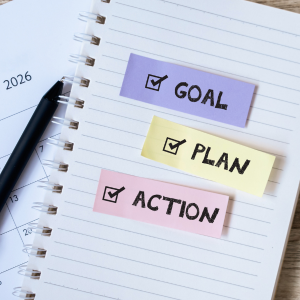 A notebook with a checkbox checked off next to the word goal, plan, and action