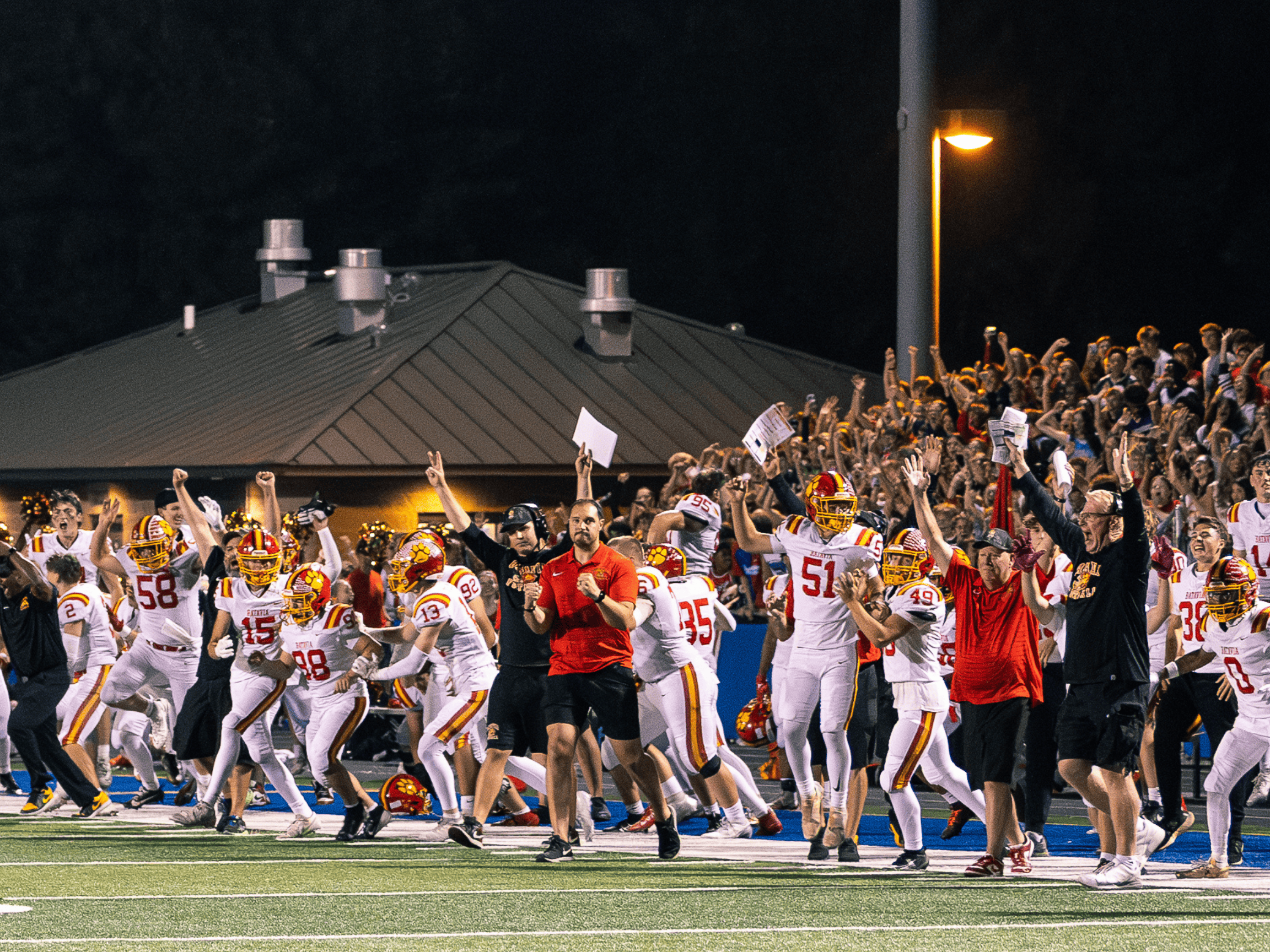 Geneva HS Football team, coaches, and fans run onto the field after winning the game