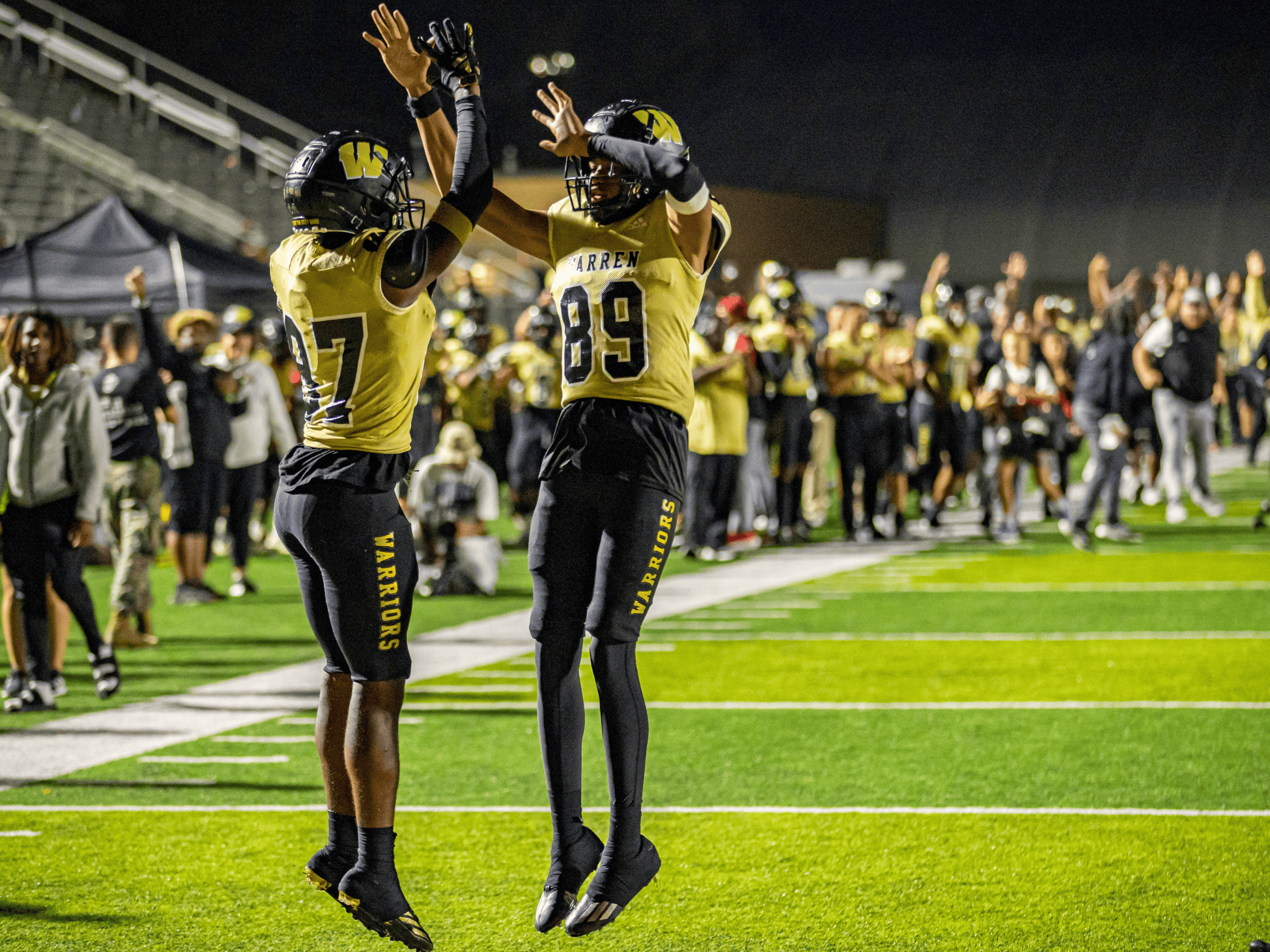 Two football players high five in the air